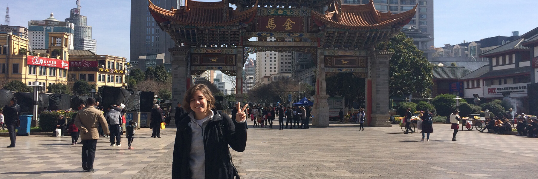 A student posing in front of a Chinese arch